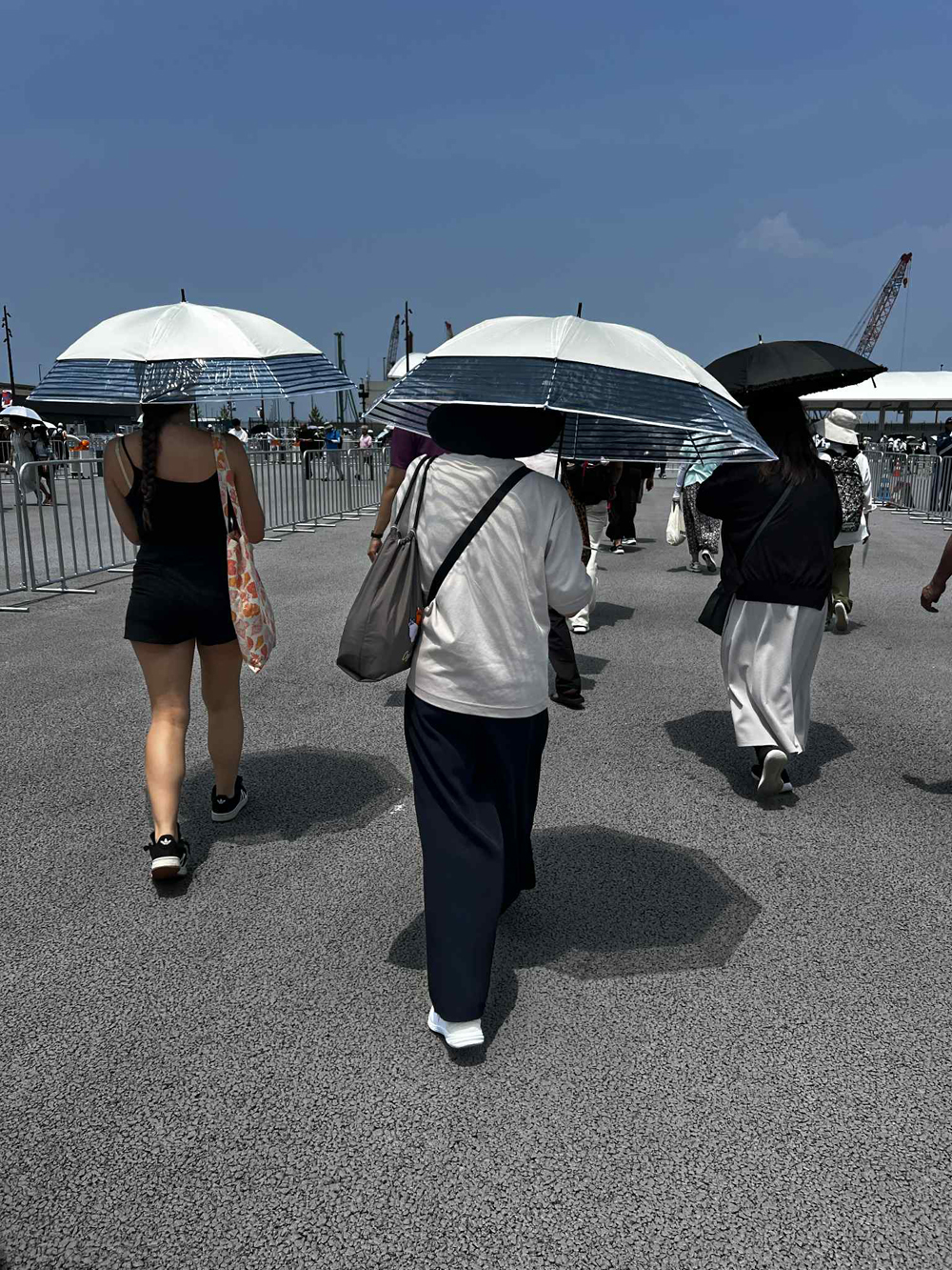 Visitors waiting at the Main Gate under loan umbrellas at Expo 2025